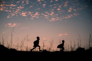 Silhouette of boys running with capes on