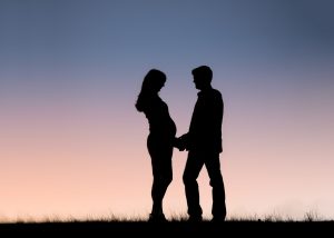 Expecting Parents holding hands at sunset