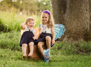 two cute girls sitting under tree
