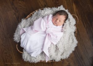 Bow swaddle baby girl asleep in basket