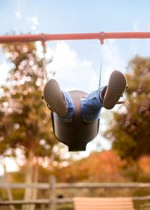 Child swinging with fall leaves
