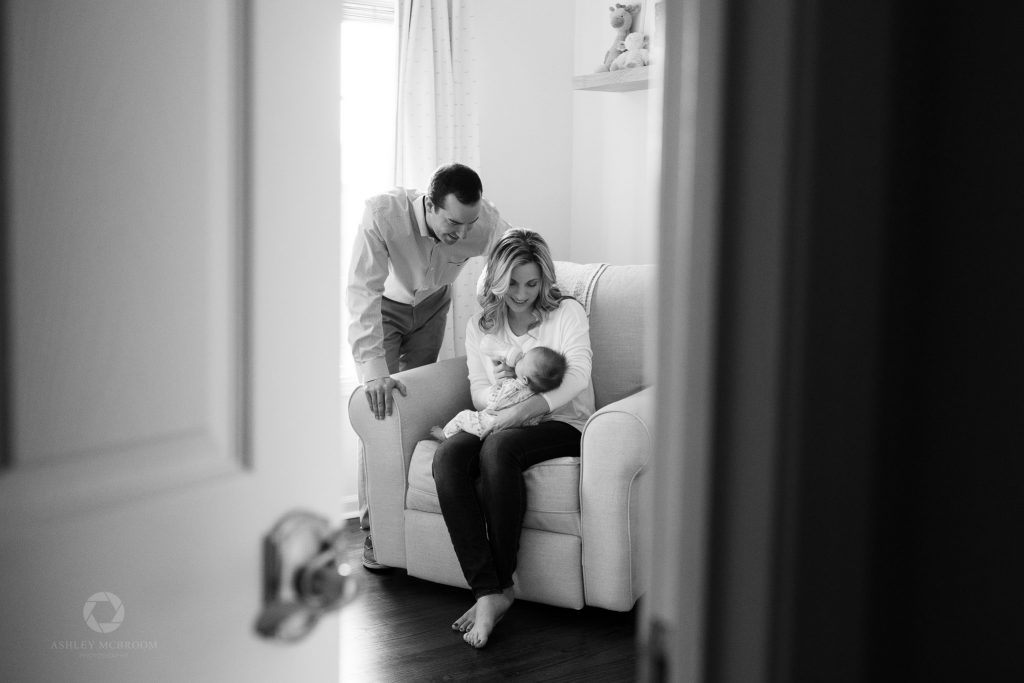 Parents looking down at baby drinking from a bottle