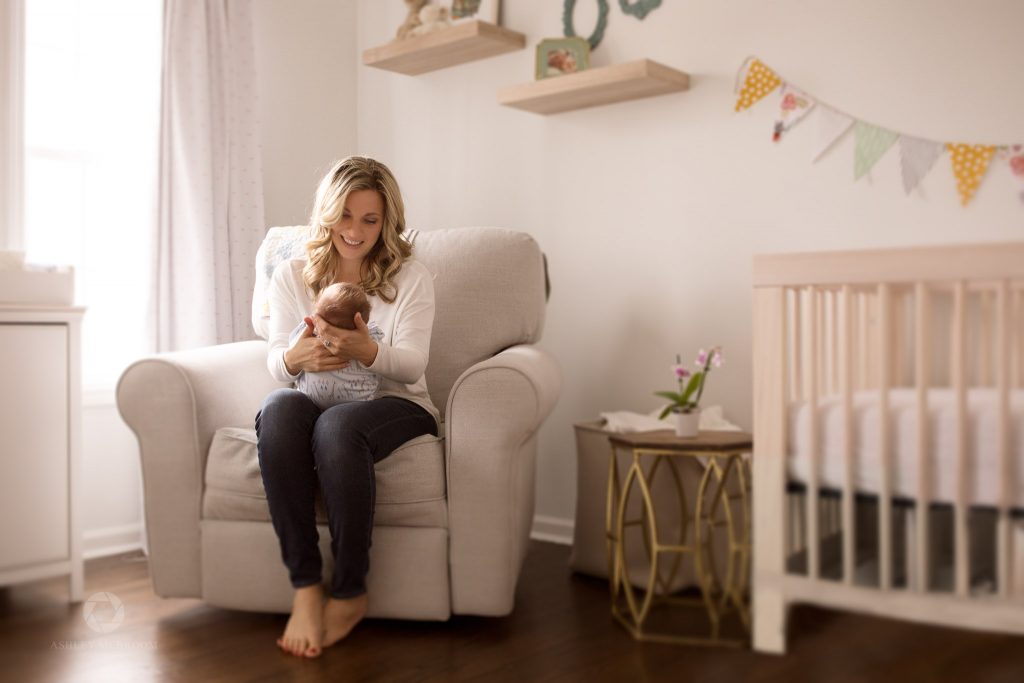 Mom with holding baby in rocker in nursery