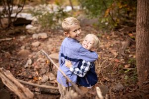 happy brothers in the woods giving a hug