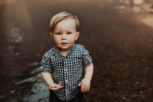 little boy in creek holding rock