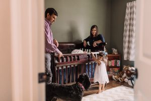 family by newborn baby's crib with dog in Dunwoody Georgia