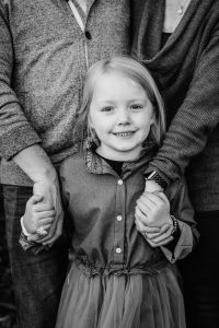 portrait of a child in black and white with parents holding hands