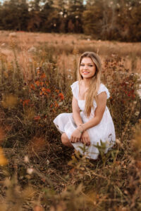 gorgeous senior photos of girl sitting in field of wild plants