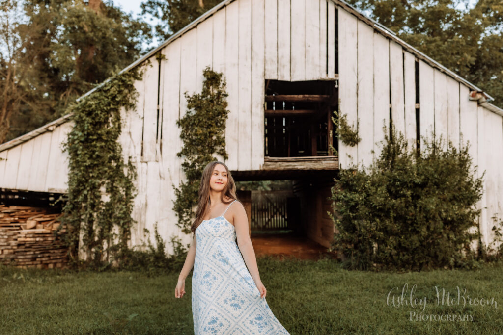 high school senior in front of a white barn during her portrait session