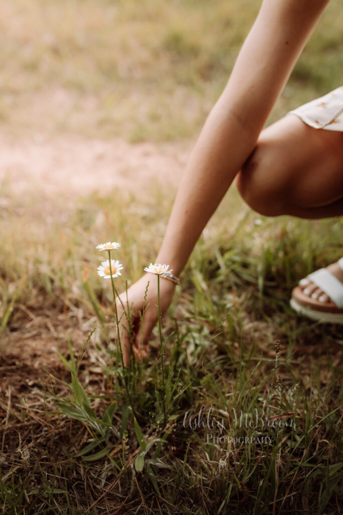 detailed shot of high school senior in Canton Georgia picking a flower