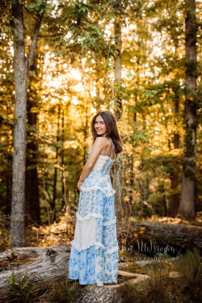 Senior girl in a blue floral dress photographed in golden evening light