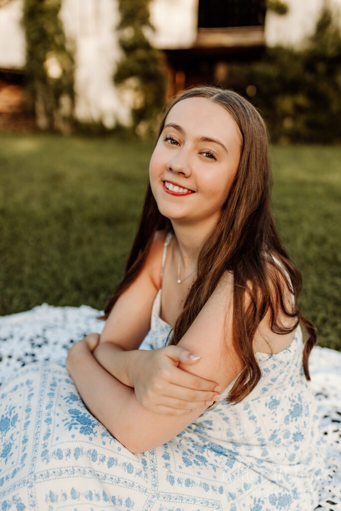 Senior portraits in Smyrna GA sitting and smiling amidst beautiful barn setting