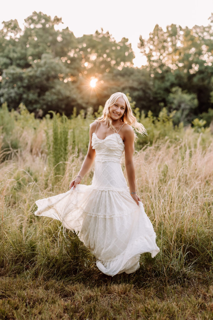 Senior girl in a flowing white dress during a golden hour field photography session in Marietta