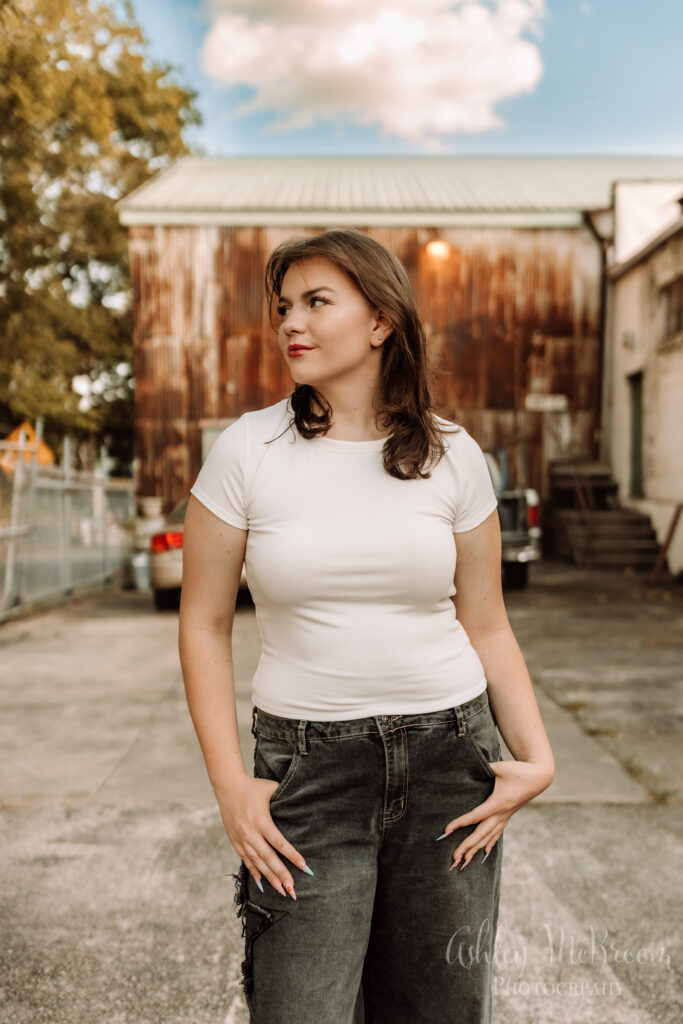urban gritty senior session with jeans and a tee in front of old rustic building