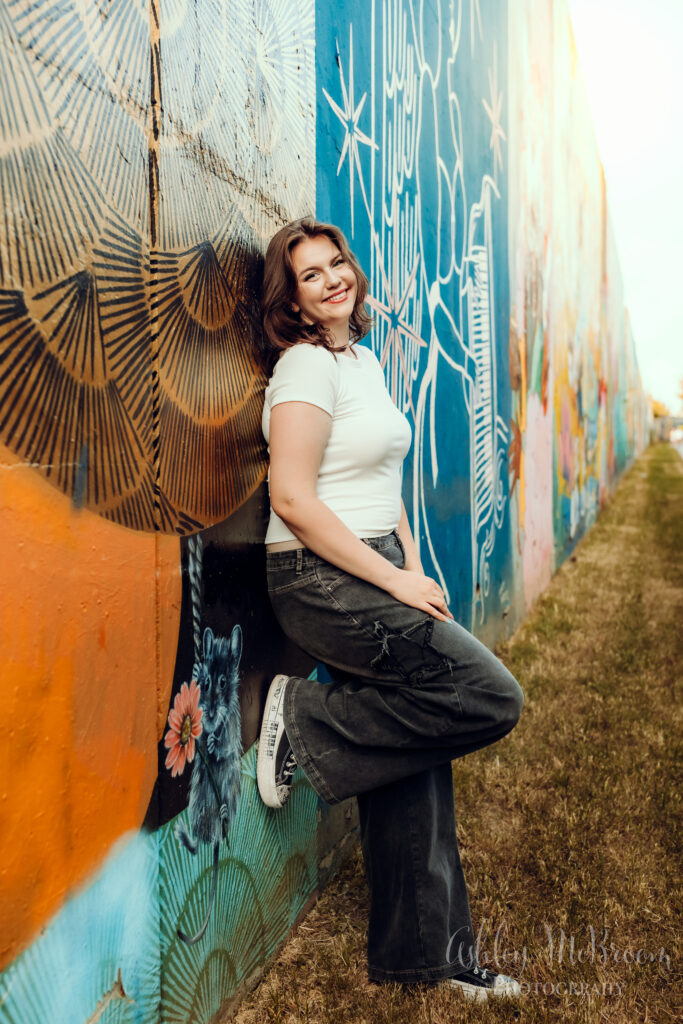 senior girl posing in front of a mural wall near the Krog St tunnel