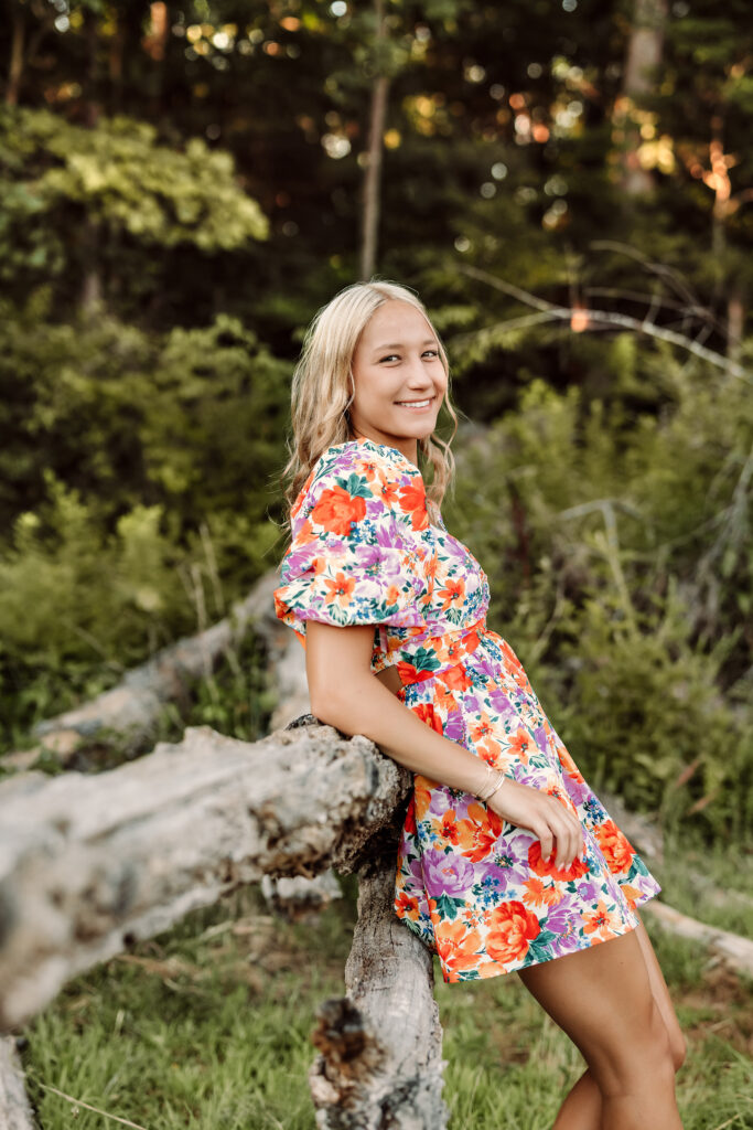 East Cobb senior portrait in a floral dress beside a rustic wooden fence