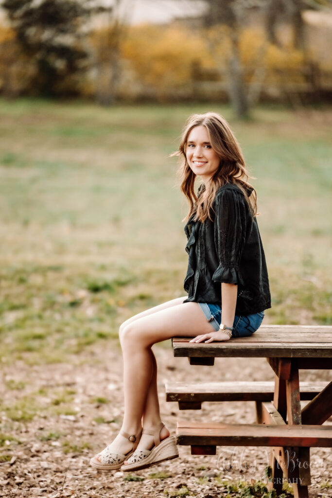 relaxed pose of high school senior sitting on picnic table