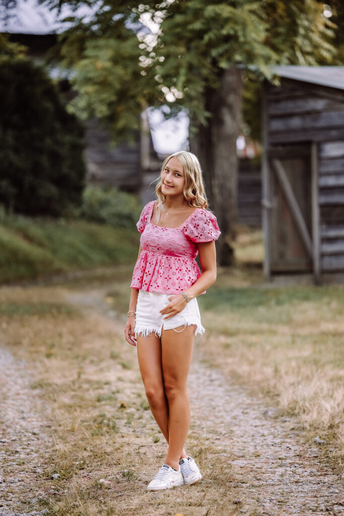 Pope High School senior in a pink top photographed near rustic buildings in Marietta, Georgia”