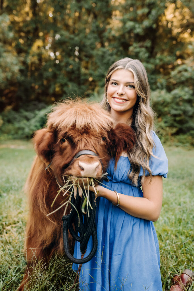 Roswell high school girl in blue dress hugging a Highland cow