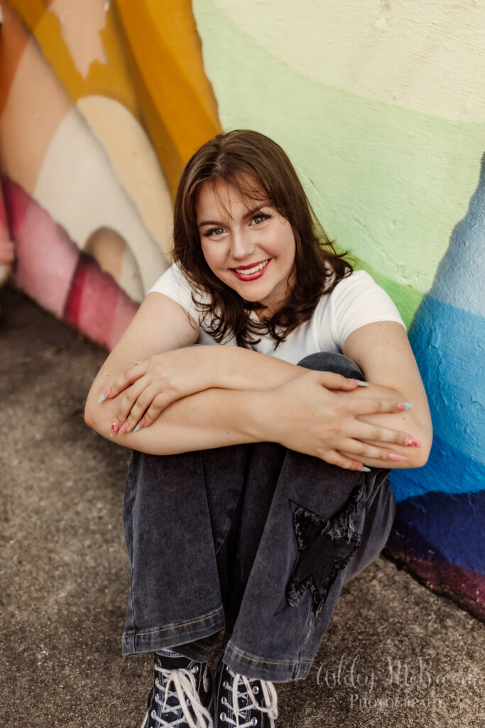 smiling happy senior for her photoshoot by rainbow wall in Atlanta