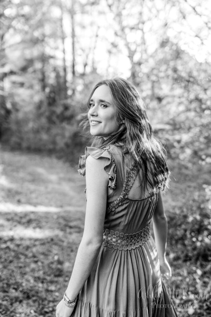 black and white image of a senior in high school walking and looking over her shoulder